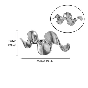 Silver wavy abstract brooch detail showing polished metal surface and pin fastener back