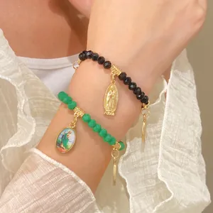 Close-up of Saint Jude and Mary portrait charms on green and black beaded bracelets