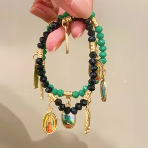 Close-up of double-layer beaded bracelet with green crystals and religious icon pendants