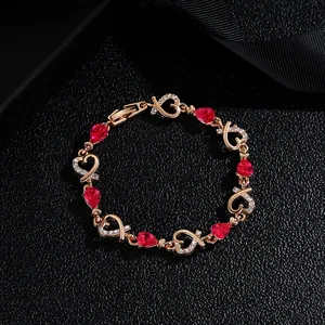 Detail of rose gold heart bracelet with ruby-like stones and white crystals on black leather