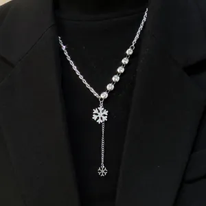 Detalle del collar en Y de copo de nieve plateado con circonitas sobre un traje negro