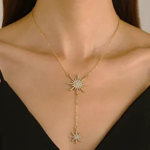 Dettaglio di un'elegante collana a Y dorata con pendenti a stella scintillanti in zircone