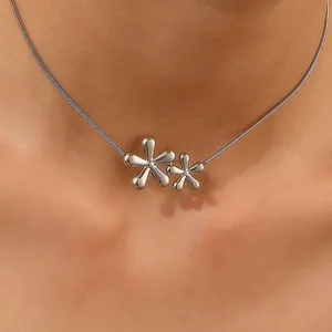 Détail du pendentif double fleur argenté sur une fine chaîne serpent portée par un modèle
