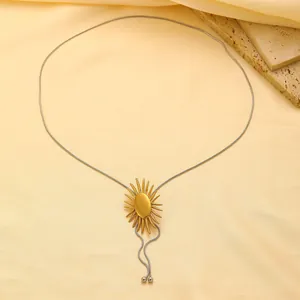 Détail du pendentif soleil doré sur chaîne serpent argentée sur fond de satin élégant