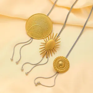 Détail de pendentifs géométriques dorés sur des chaînes serpent argentées sur du satin