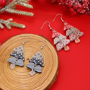 Detailed view of festive Christmas tree drop earrings with layered patterns on wooden base