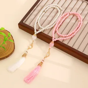 Close-up of Muslim Tasbih prayer beads in cream and pink with golden moon charms