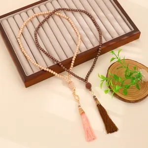 Close-up of champagne and coffee pearl prayer beads with long silk tassels on wood