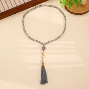 Detailed view of grey faux pearl prayer beads with golden crescent and silk tassel