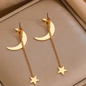 Elegante goldene Mond und Stern Quastenohrringe auf luxuriösem Seidenstoff präsentiert