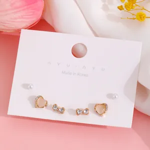 Primer plano de set de pendientes dorados con perlas y strass sobre cartón