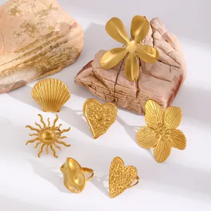 Set of chunky gold rings featuring sun, heart, and floral motifs on natural stone