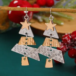 Christmas tree drop earrings in gold and silver metal hanging on a festive pine branch
