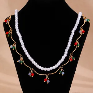 Double-layered gold chain necklace with pearls and colorful bead charms on bust