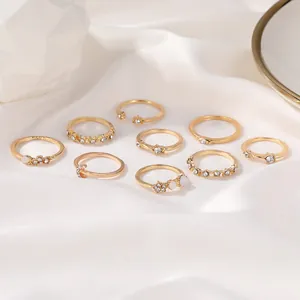 Makroaufnahme von 10 Goldlegierungsringen mit Zirkon und Perlen auf weißem Seidenstoff