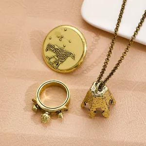 Close-up of vintage gold bird brooch, bell ring and textured cone necklace set