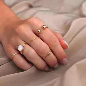 Detailansicht eines fünfteiligen goldenen Ringsets mit weißem Steininlay auf Seidenstoff