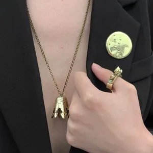 Vintage gold jewelry set featuring a bird brooch, crown ring, and bell necklace on a black suit