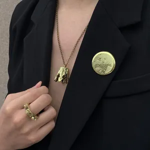 Close-up of vintage gold rings, bell necklace, and engraved bird brooch on a black blazer