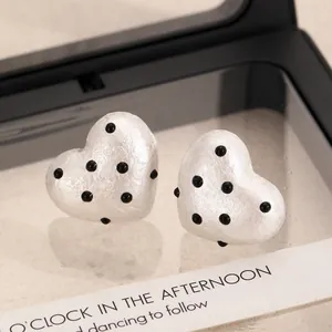 Close-up of heart-shaped polka dot earrings in a black jewelry box for woman