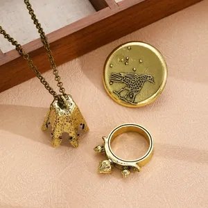 Retro gold jewelry set including textured pendant necklace, bird motif badge and beaded ring