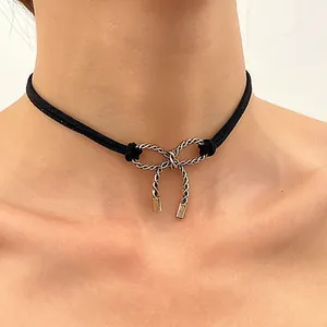Detail eines schwarzen Samt-Chokers mit strukturiertem Silber-Schleifenanhänger und Kordel