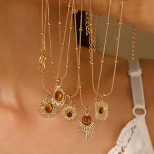 Layered gold necklaces with tiger eye pendants in sunburst and teardrop bohemian designs