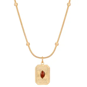 Golden necklace with sunburst sunray pendant and red-brown oval gemstone inlay