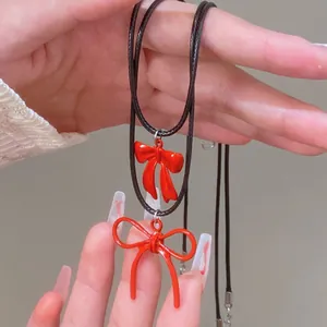Detalle de los colgantes de lazo rojo con cordones de cuero negro y aleación sólida