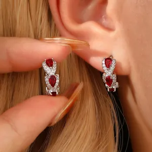 Close-up of model wearing pear-cut red gemstone earrings with micro-pave crystals