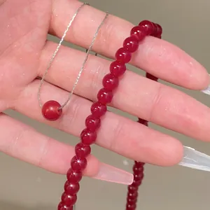 Detalle de un collar de cuentas rojas y una cadena de plata con colgante rojo