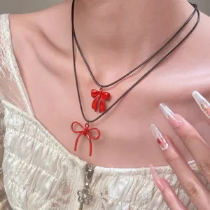 Collar con colgante de lazo rojo y cordón negro mostrado en una modelo de moda