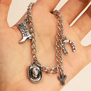 Détail du bracelet en argent vintage avec breloques de botte, chapeau et cactus de cowboy