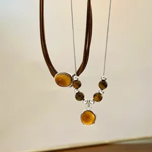 Detail of vintage layered tiger eye stone necklaces with woven cord and silver metal chain