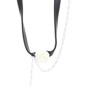 Detail of black choker with white resin rose, pearl tassel, and metallic accents