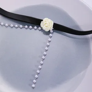Detail of a white resin rose choker with black strap and hanging pearl fringe