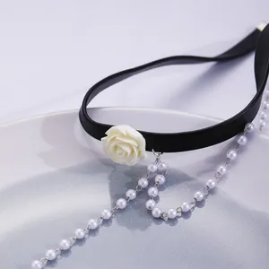Macro shot of a vintage choker with a white resin rose and long faux pearl tassels