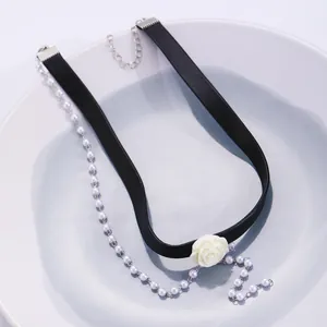Detail of black choker with white resin rose and hanging pearl chain on ceramic plate