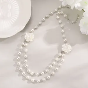 Detail of elegant double-layer white pearl necklace featuring two white rose pendants