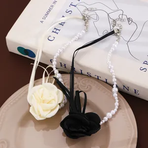 Detail view of pearl necklaces with large fabric roses in black and beige finishes