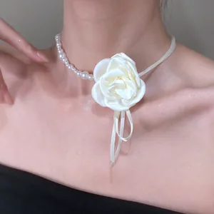 Detail of white fabric rose necklace with faux pearls and satin ribbons on a model neck