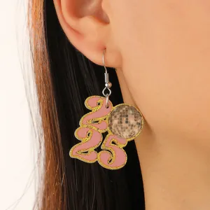 Detail of 2025 pink glitter number earrings with disco ball charm for New Year