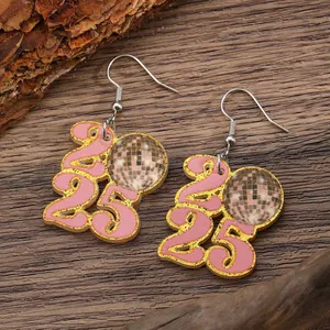 Detailed view of 2025 disco ball earrings with pink and gold glitter on wooden texture