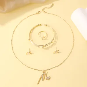 Detailed close-up of golden four-piece jewelry set featuring letter M pendant and crystals