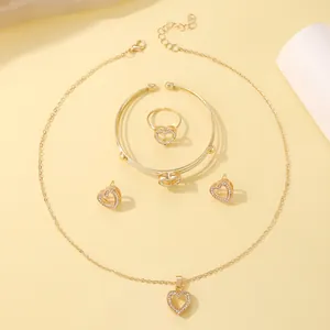 Elegant four-piece gold jewelry set with heart-shaped crystal necklace, ring, bracelet and earrings
