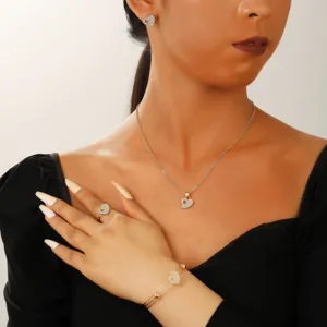 Gold heart jewelry set with emerald zircon stones worn by model on black outfit