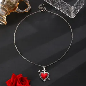 Macro shot of vintage silver snake chain with a sacred heart pendant and red rose decoration