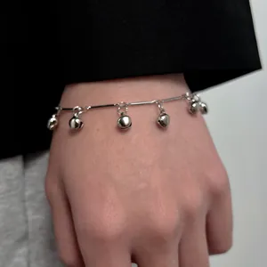 Y2K style silver bell bracelet with six round polished charms on a double layer chain