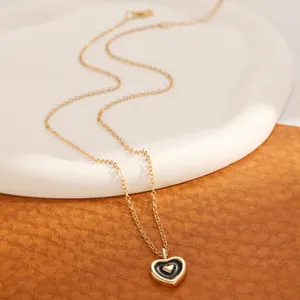 Elegant gold and black enamel heart pendant necklace on a refined ceramic base