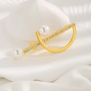 Elegant geometric gold brooch with white pearls and zircons on white fabric